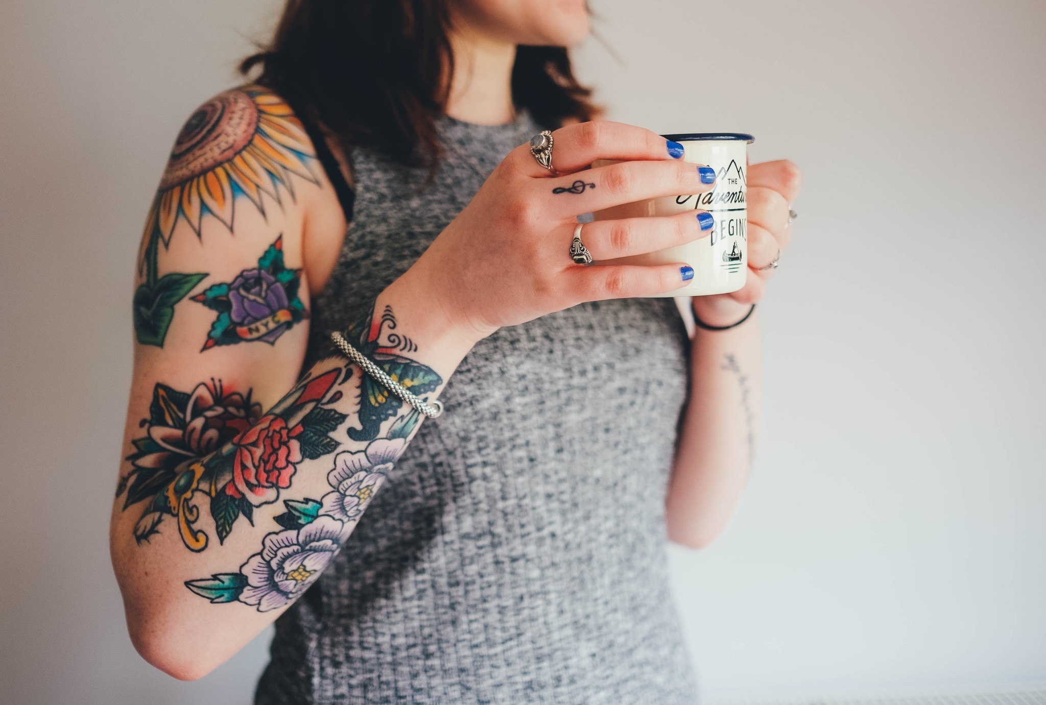 portrait d'une femme qui boit un thé et qui a les bras tatoués